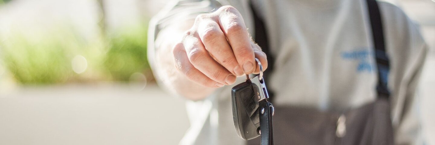 Hand holding out an unbranded car key fob