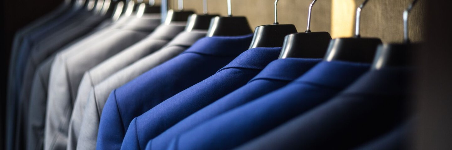 Navy and gray suit jackets hanging on a retail rack