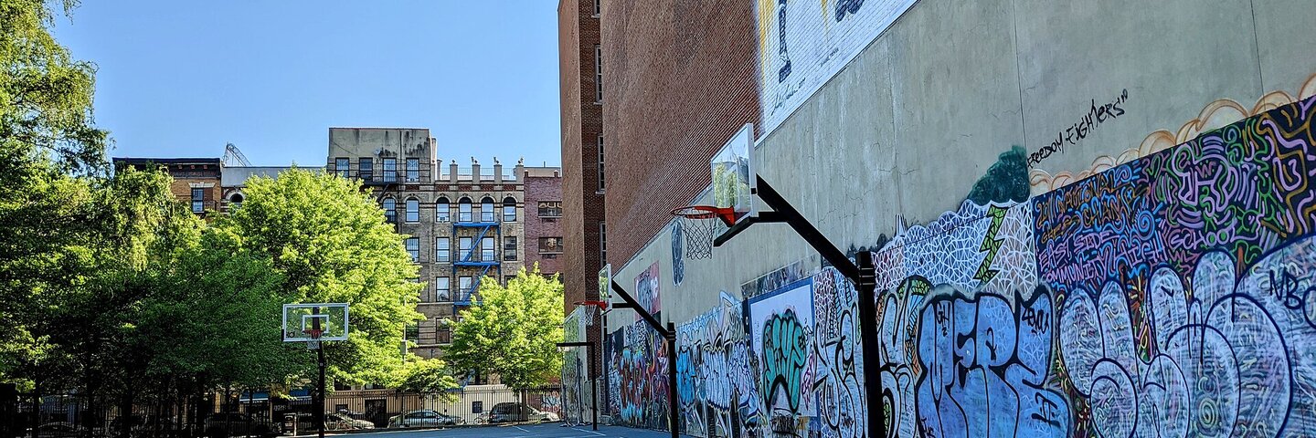 Outdoor basketball court with hoops and a graffiti wall