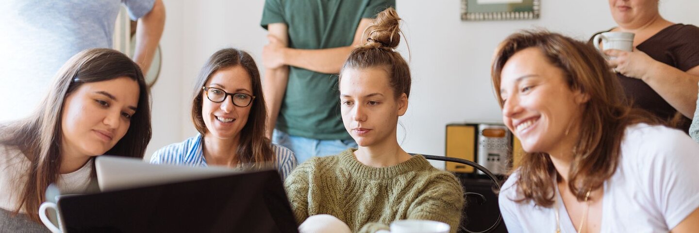 People gathered around a laptop in a bright room