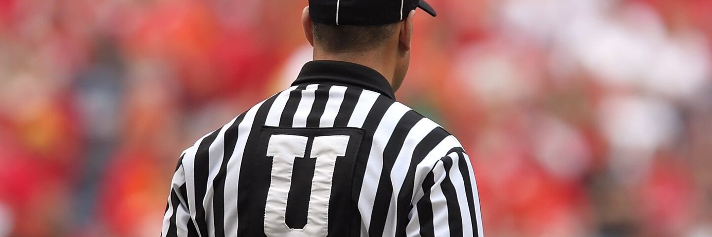 American football official in a striped jersey, seen from behind