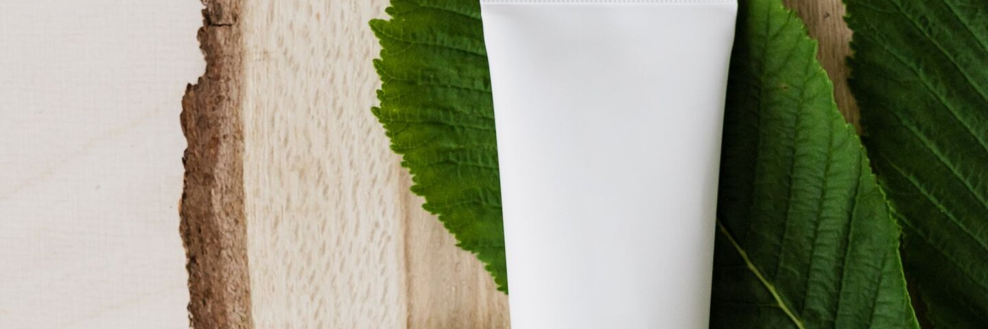 Unbranded white cream tube on green leaves
