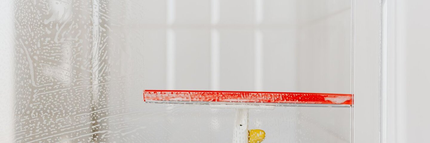 Gloved hand cleaning glass with a squeegee