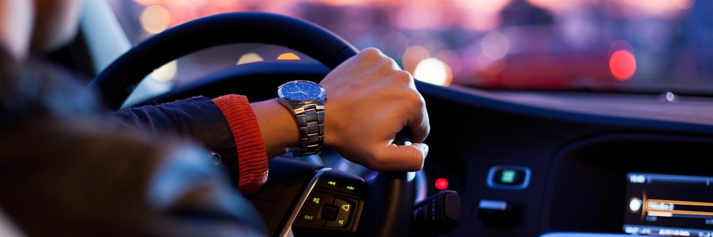 Driver’s hand on a steering wheel at dusk