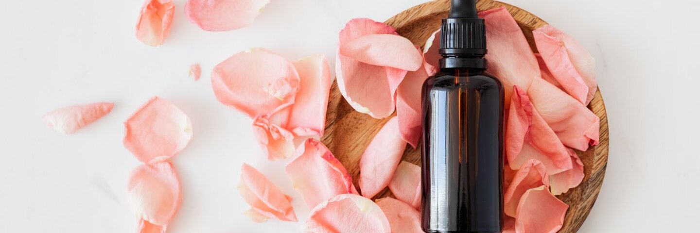 Amber dropper bottle in a wooden dish with rose petals
